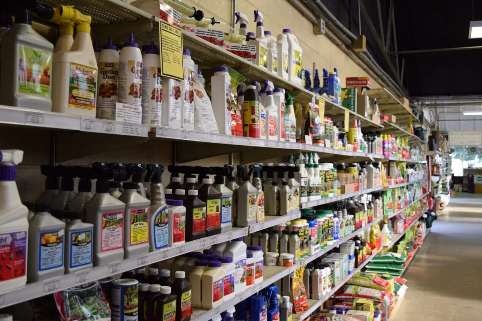 Aisle in a store stocked with various garden supplies and pest control products on shelves.