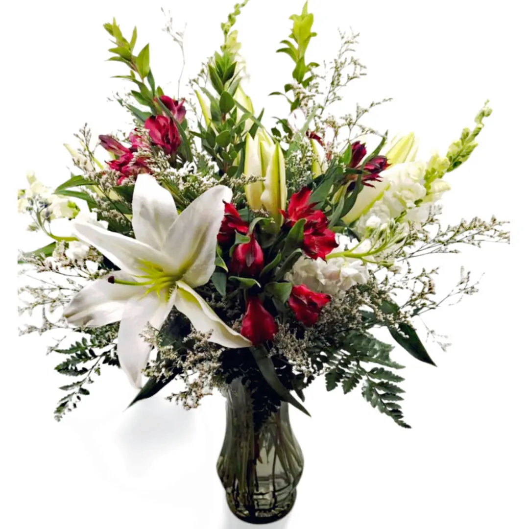 Arrangement of white lilies, white stock, red alstroemeria, white Limonium, white snapdragons, myrtle and leather greens.